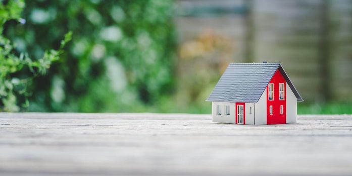 Red house model on the floor, outdoors. Concept for new home, property and estate, copy space