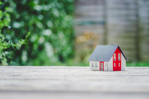 Red house model on the floor, outdoors. Concept for new home, property and estate, copy space