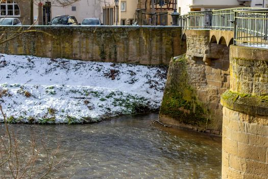 The river glan and stone bridge in Meisenheim in winter with snow