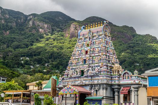 Hindu temple with colorful facade called Arulmihu Navasakti Vinayagar Temple in Victoria on Seychelles island mahé with mountain range in the background