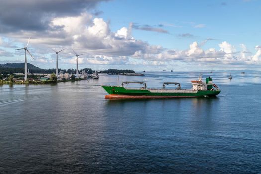 Port Victoria on Seychelles island mahé with cargo ship in front and wind wheels in the background