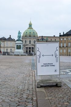 Copenhagen, Denmark - December 31, 2020: Sign on Amalienborg Palace Square reminding people to keep distance to each other due to corona virus.