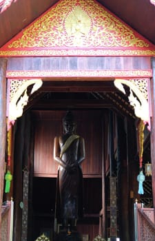 standing buddha statue stupa in asian wooden buddhist temple in Thailand