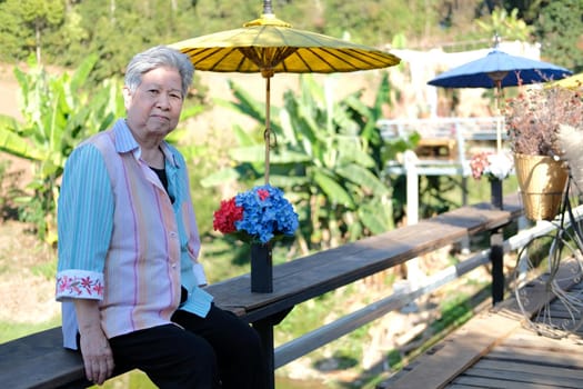asian old elder woman elderly female relaxing resting on terrace balcony. senior leisure lifestyle