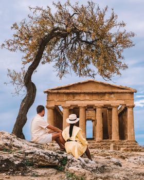 couple watching old temple during a vacation at the Italian Island Sicily visiting the archeological site of Agrigento valley of the temples. Sicilia