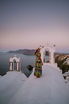 Sunset at the Island Of Santorini Greece, beautiful whitewashed village Oia with church and windmill during sunset, streets of Oia Santorini during summer vacation at the Greek Island Woman on luxury vacation Greece