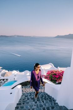 Sunset at the Island Of Santorini Greece, beautiful whitewashed village Oia with church and windmill during sunset, streets of Oia Santorini during summer vacation at the Greek Island Woman on luxury vacation Greece