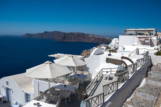 Santorini, Greece. Picturesq view of traditional cycladic Santorini houses on small street with flowers in foreground. Location: Oia village, Santorini, Greece. Vacations background Europe