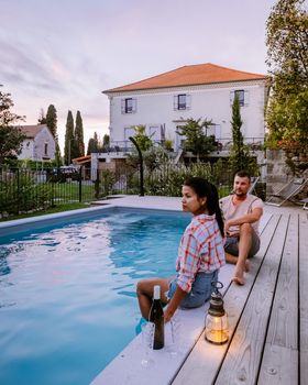 French vacation home with wooden deck and swimming pool in the Ardeche France Europe. Couple relaxing by the pool with wooden deck during luxury vacation at an holiday home in South of France