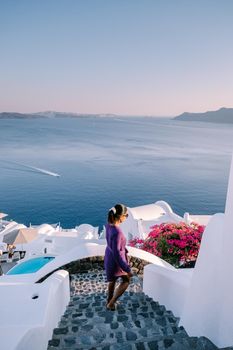 Sunset at the Island Of Santorini Greece, beautiful whitewashed village Oia with church and windmill during sunset, streets of Oia Santorini during summer vacation at the Greek Island Woman on luxury vacation Greece