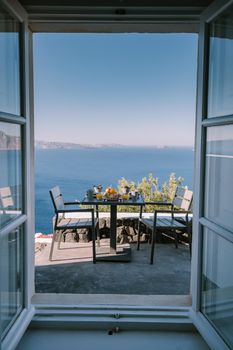 couple having breakfast at traditional cave house Santorini Greece, beautiful whitewashed village Oia with church and windmill during sunset, streets of Oia Santorini during summer vacation at the Greek Island