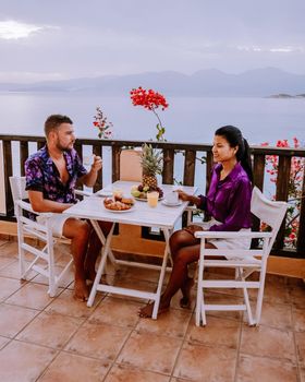 table and chairs with breakfast during sunrise at the meditarian sea in Greece. Couple having breakfast on balcony looking out over the ocean