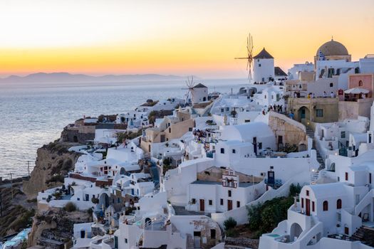 Sunset at the Island Of Santorini Greece, beautiful whitewashed village Oia with church and windmill during sunset, streets of Oia Santorini during summer vacation at the Greek Island