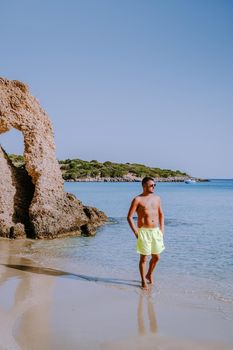 Tropical beach of Voulisma beach, Istron, Crete, Greece ,Most beautiful beaches of Crete island -Istron bay near Agios Nikolaos , young guy mid age on vacation Crete at the beach