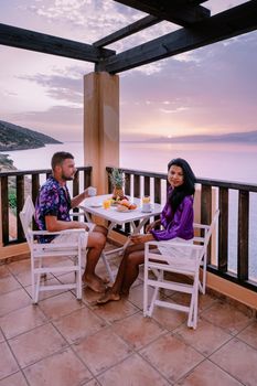 table and chairs with breakfast during sunrise at the meditarian sea in Greece. Couple having breakfast on balcony looking out over the ocean