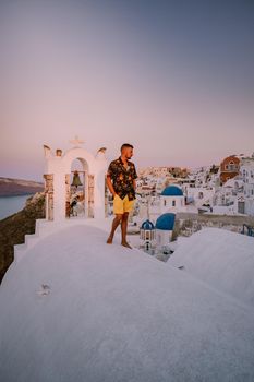 Sunset at the Island Of Santorini Greece, beautiful whitewashed village Oia with church and windmill during sunset, streets of Oia Santorini during summer vacation at the Greek Island, young men on luxury vacation Santorini