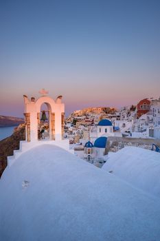 Sunset at the Island Of Santorini Greece, beautiful whitewashed village Oia with church and windmill during sunset, streets of Oia Santorini during summer vacation at the Greek Island