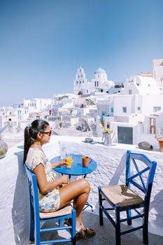 Santorini Greece, young woman on luxury vacation at the Island of Santorini watching sunrise by the blue dome church and whitewashed village of Oia Santorini Greece during sunrise during summer vacation, men and woman on holiday in Greece