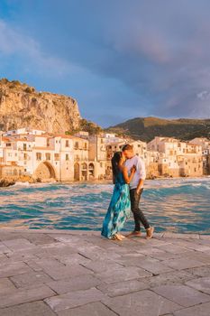 Cefalu Sicily, a couple watching the sunset at the beach of Cefalu Sicilia Italy, mid-age men and woman on vacation Sicily. 