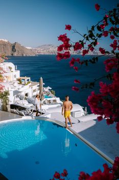 Santorini Greece, young couple on luxury vacation at the Island of Santorini watching sunrise by the blue dome church and whitewashed village of Oia Santorini Greece during sunrise during summer vacation, men and woman on holiday in Greece