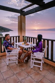 table and chairs with breakfast during sunrise at the meditarian sea in Greece. Couple having breakfast on balcony looking out over the ocean