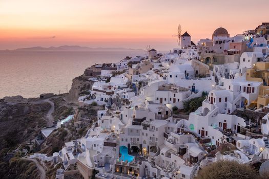 Sunset at the Island Of Santorini Greece, beautiful whitewashed village Oia with church and windmill during sunset, streets of Oia Santorini during summer vacation at the Greek Island