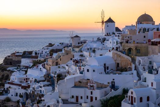 Sunset at the Island Of Santorini Greece, beautiful whitewashed village Oia with church and windmill during sunset, streets of Oia Santorini during summer vacation at the Greek Island