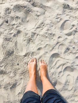 Woman stands barefoot on beach sand. Long-awaited vacation. Journey to countries with warm climate. Tactile pleasure.