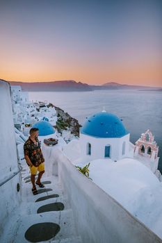 Sunset at the Island Of Santorini Greece, beautiful whitewashed village Oia with church and windmill during sunset, streets of Oia Santorini during summer vacation at the Greek Island, young men on luxury vacation Santorini