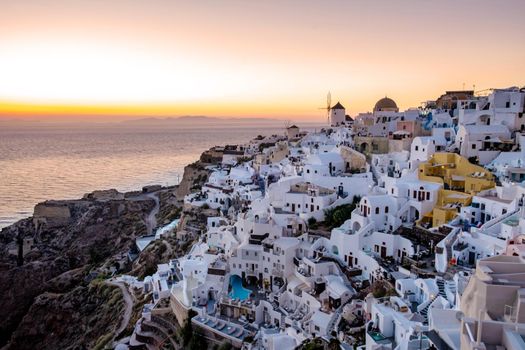 Sunset at the Island Of Santorini Greece, beautiful whitewashed village Oia with church and windmill during sunset, streets of Oia Santorini during summer vacation at the Greek Island