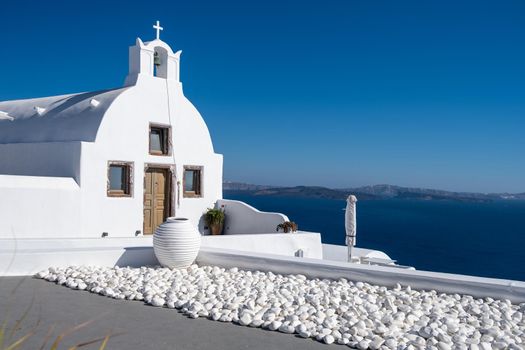 Sunset at the Island Of Santorini Greece, beautiful whitewashed village Oia with church and windmill during sunset, streets of Oia Santorini during summer vacation at the Greek Island