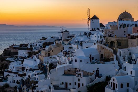 Sunset at the Island Of Santorini Greece, beautiful whitewashed village Oia with church and windmill during sunset, streets of Oia Santorini during summer vacation at the Greek Island