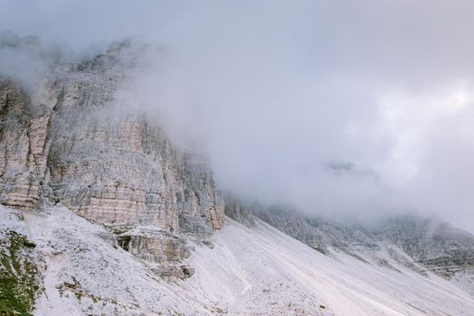 hiking in the italian dolomites during foggy weather with clouds, Stunning view to Tre Cime peaks in Dolomites, Italy. Europe