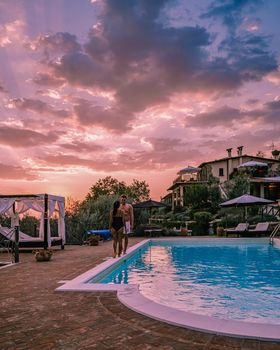 Luxury country house with swimming pool in Italy. Pool and old farm house during sunset central Italy. Couple on Vacation at luxury villa in Italy, men and woman watching sunset