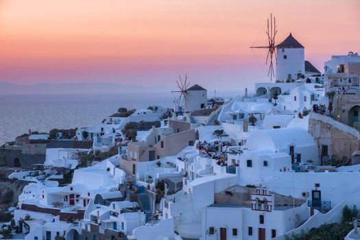 Sunset at the Island Of Santorini Greece, beautiful whitewashed village Oia with church and windmill during sunset, streets of Oia Santorini during summer vacation at the Greek Island