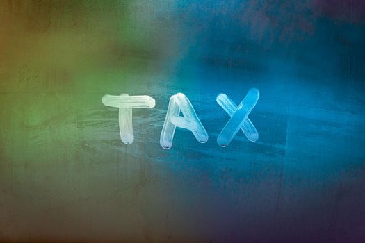 word tax hadwritten on night wet window glass surface with green and orange colors in blurry background