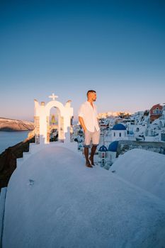 Sunset at the Island Of Santorini Greece, beautiful whitewashed village Oia with church and windmill during sunset, streets of Oia Santorini during summer vacation at the Greek Island, young men on luxury vacation Santorini