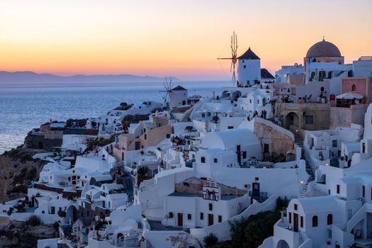 Sunset at the Island Of Santorini Greece, beautiful whitewashed village Oia with church and windmill during sunset, streets of Oia Santorini during summer vacation at the Greek Island