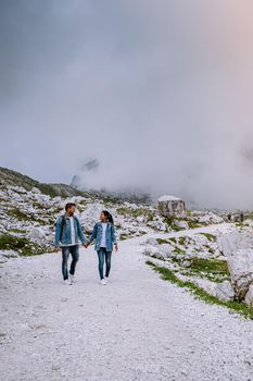 couple hiking in the italian dolomites during foggy weather with clouds, Stunning view to Tre Cime peaks in Dolomites, Italy. Europe