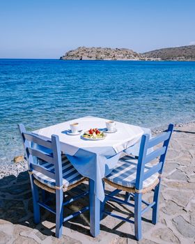 Crete Greece Plaka Lassithi with is traditional blue table and chairs and the beach in Crete Greece. Paralia Plakas, Plaka village Crete