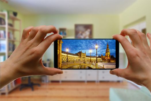 Online travel to Seville, Spain from home using a mobile phone. Plaza de Espana on the smartphone screen