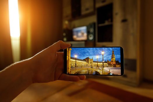 Online travel to Seville, Spain from home using a mobile phone. Plaza de Espana on the smartphone screen