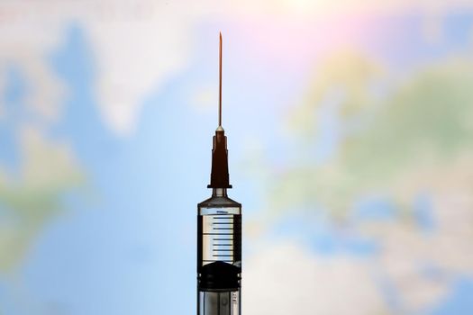 Syringe with vaccine on world map background