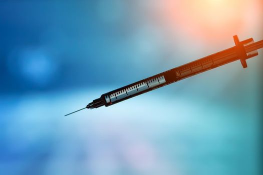 Syringe with vaccine on blue background