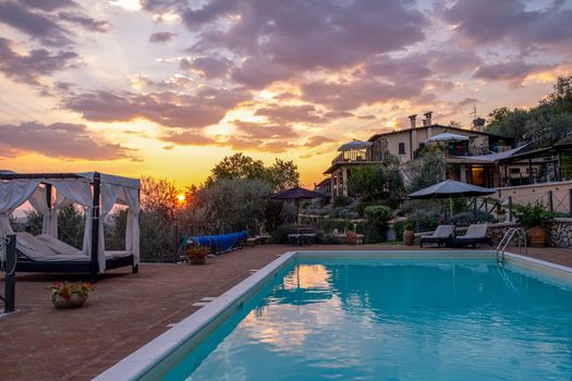 Luxury country house with swimming pool in Italy. Pool and old farm house during sunset central Italy