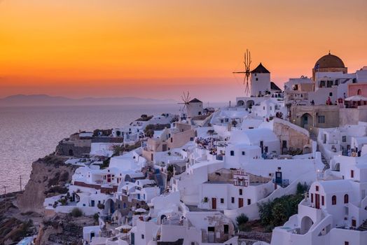 Sunset at the Island Of Santorini Greece, beautiful whitewashed village Oia with church and windmill during sunset, streets of Oia Santorini during summer vacation at the Greek Island