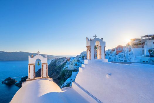 Sunset at the Island Of Santorini Greece, beautiful whitewashed village Oia with church and windmill during sunset, streets of Oia Santorini during summer vacation at the Greek Island