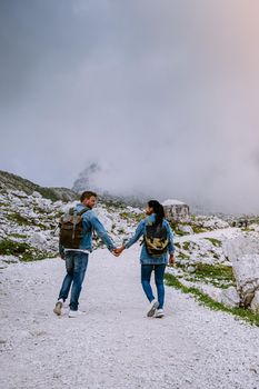 couple hiking in the italian dolomites during foggy weather with clouds, Stunning view to Tre Cime peaks in Dolomites, Italy. Europe