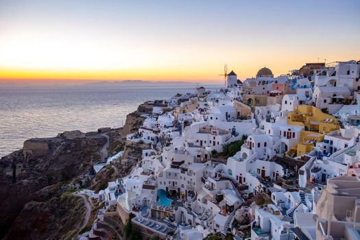 Sunset at the Island Of Santorini Greece, beautiful whitewashed village Oia with church and windmill during sunset, streets of Oia Santorini during summer vacation at the Greek Island