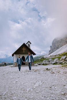 couple hiking in the italian dolomites during foggy weather with clouds, Stunning view to Tre Cime peaks in Dolomites, Italy. Europe